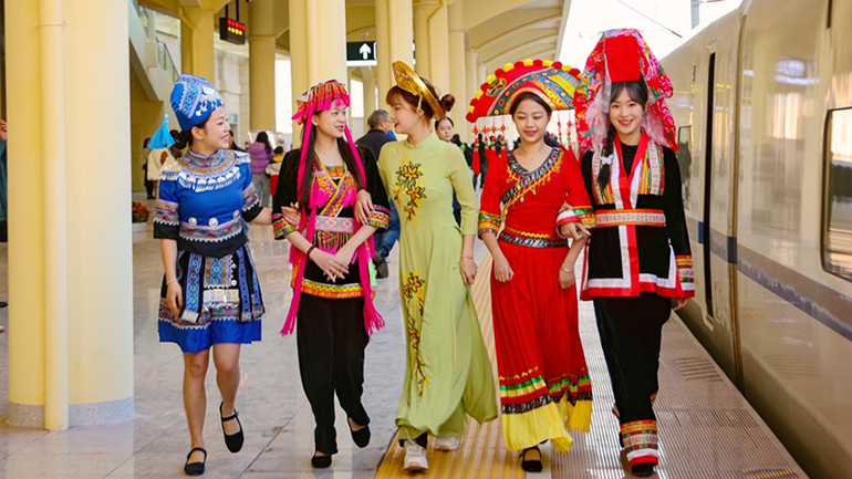 Hành khách trong trang phục truyền thống chuẩn bị lên tàu. (Ảnh: People.cn)