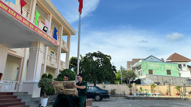 Thượng úy Nguyễn Văn Đức (bên phải), Đội trưởng đội vận động quần chúng tìm hiểu lịch sử dưới lá cờ Tổ quốc.