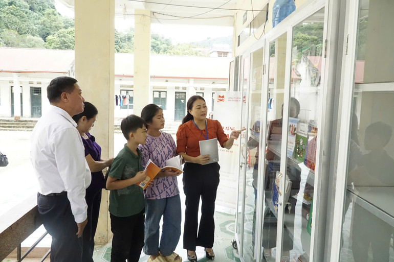 Cô giáo Lục Thị Hạnh (người mặc áo màu cam), Hiệu trưởng Trường phổ thông dân tộc nội trú trung học cơ sở Bảo Lạc giới thiệu tủ sách tới học sinh. (Ảnh: MINH TUẤN)