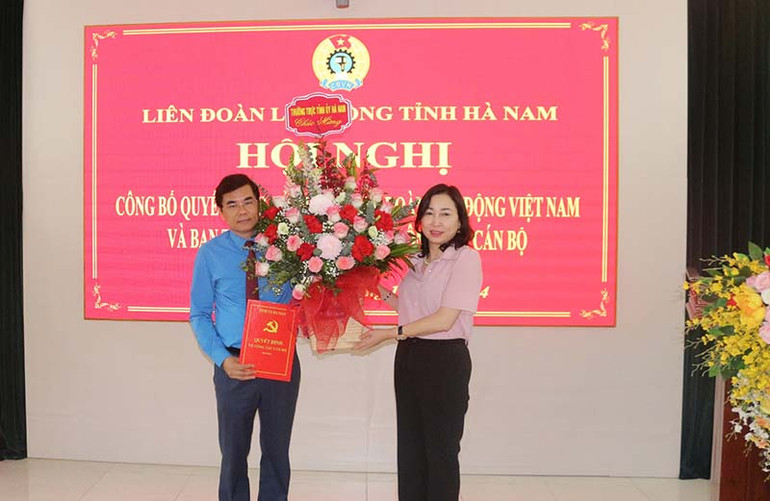 Đồng chí Phó Bí thư Thường trực Tỉnh ủy Đinh Thị Lụa trao quyết định và tặng hoa chúc mừng đồng chí Nguyễn Hải Long.