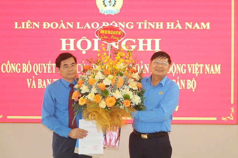 Đồng chí Phan Văn Anh, Phó Chủ tịch Tổng Liên đoàn Lao động Việt Nam, trao quyết định và tặng hoa chúc mừng đồng chí Nguyễn Hải Long.