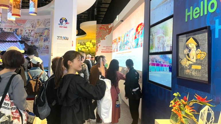 Du khách thích thú xem tranh đậu bạc của Việt Nam. (Ảnh: Cục Hợp tác quốc tế)