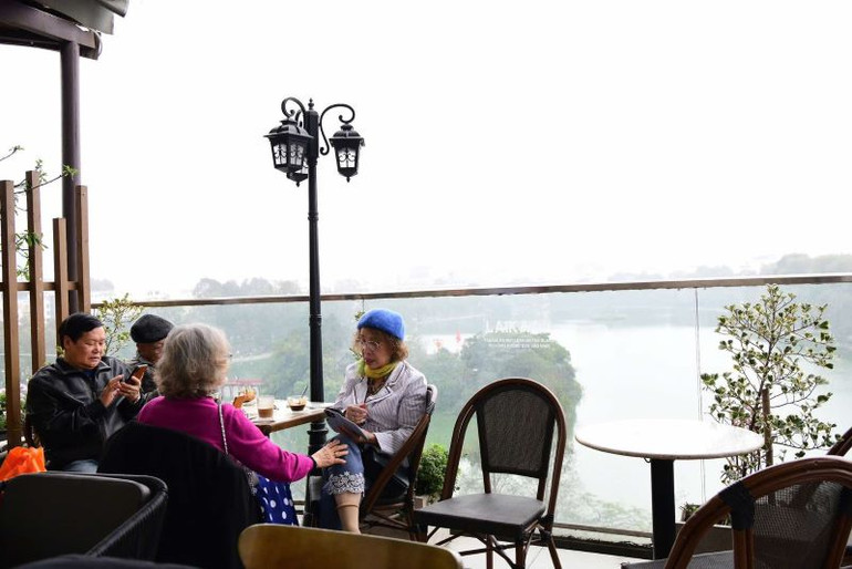 Người dân chọn vị trí ngồi trên cao từ tòa nhà thưởng thức cảnh đẹp Hồ Gươm trọn tầm mắt. (Ảnh: Thế Dương)