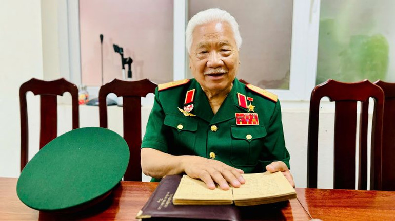 Thiếu tướng Nguyễn Đăng Kính và cuốn sổ nhật ký bay luôn cầm bên người. (Ảnh: HNV)