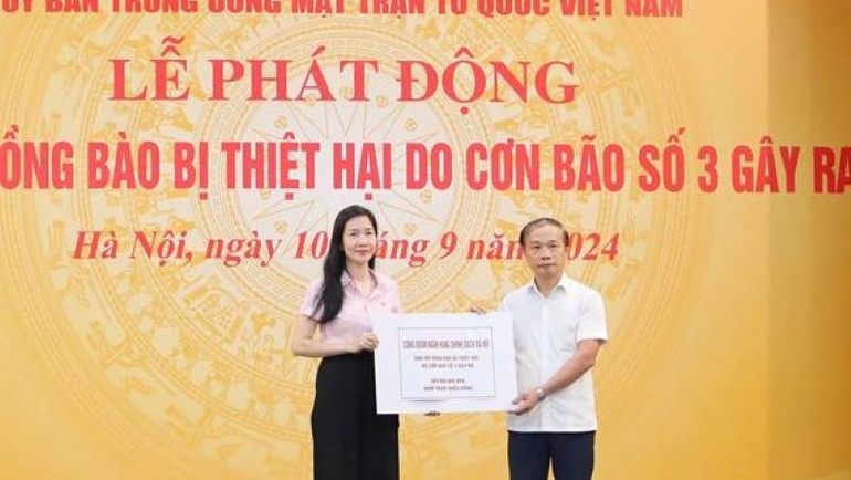 Phó Tổng Giám đốc Ngân hàng Chính sách xã hội Nguyễn Thị Hằng (bên trái) trao biểu trưng cho đại diện Lãnh đạo Mặt trận Tổ quốc Việt Nam.