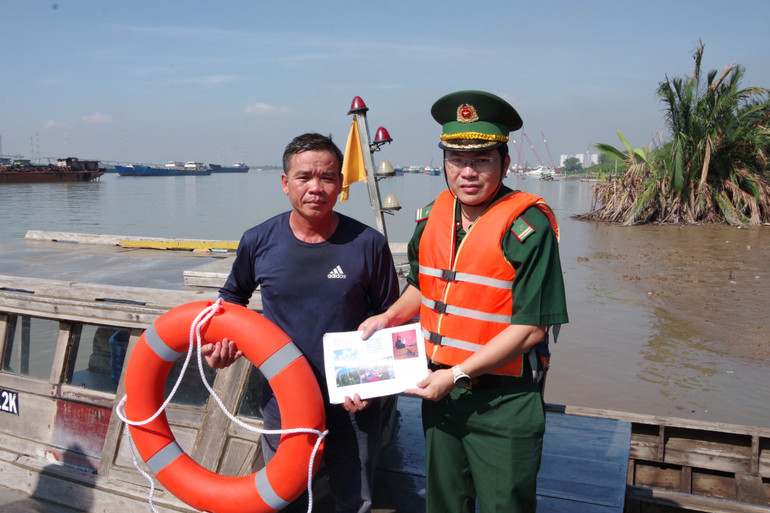 Trung tá Tạ Đức Trong, Chính trị viên Trạm kiểm soát Biên phòng cửa khẩu cảng Hiệp Phước phát tờ rơi và tặng phao cứu sinh cho chủ phương tiện. (Ảnh: Mai Lan) Trung tá Tạ Đức Trong, Chính trị viên Trạm kiểm soát Biên phòng cửa khẩu cảng Hiệp Phước phát tờ rơi và tặng phao cứu sinh cho chủ phương tiện. (Ảnh: Mai Lan)