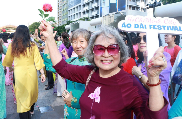 Những người bà, người mẹ hào hứng vẫy chào đoàn khách mời trình diễn áo dài.