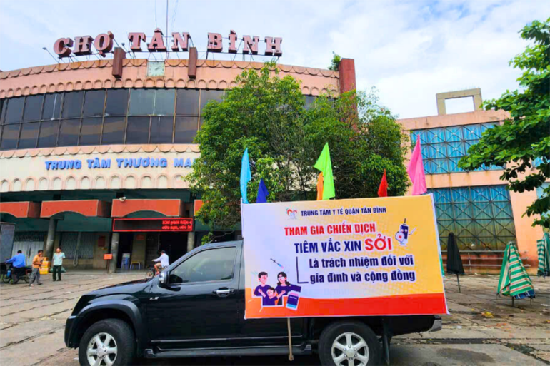 Một xe loa đi qua các khu phố tại quận Tân Bình, phát thông báo vận động người dân đưa trẻ đến các điểm tiêm chủng.