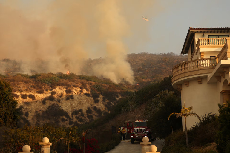 Lính cứu hỏa làm việc gần một ngôi nhà khi khói lửa bốc lên nghi ngút.
