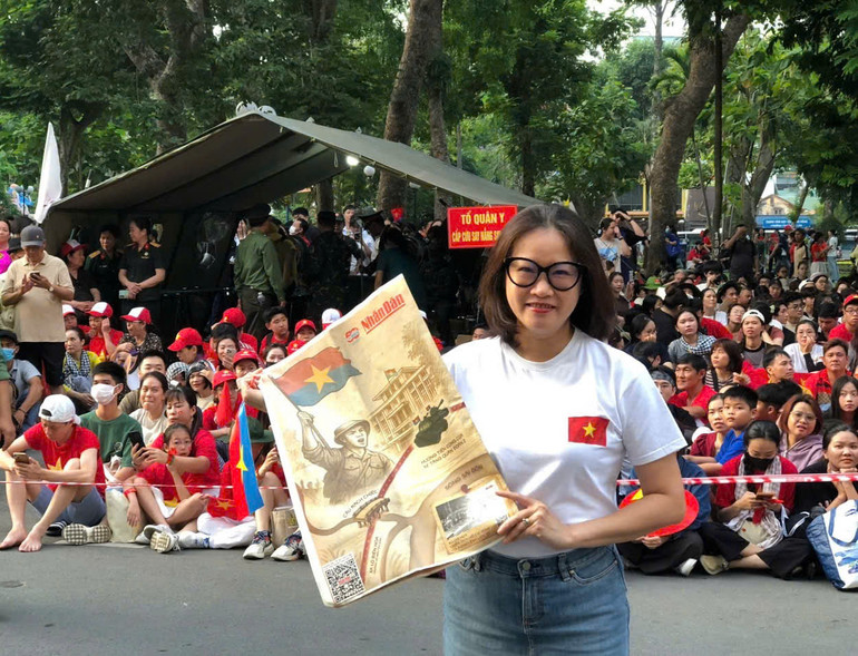 Sáng sớm 30/4, bạn Hương ở quận 7, TP Hồ Chí Minh mang Phụ san đặc biệt của Báo Nhân Dân chờ bên đường Lê Lai, Công viên 23/9, để chào đón đoàn diễu hành kỷ niệm 50 năm Ngày Giải phóng miền nam, thống nhất đất nước.