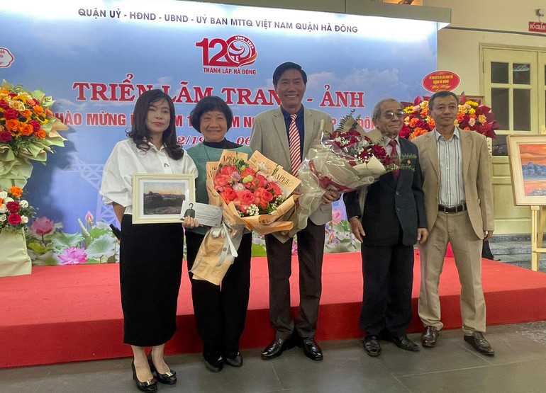 Họa sĩ Đặng Thị Khuê, nguyên đại biểu Quốc hội khóa VII, nguyên Thư ký Hội nghệ sĩ tạo hình Việt Nam tặng hoa, quà cho họa sĩ Nguyễn Văn Trường.