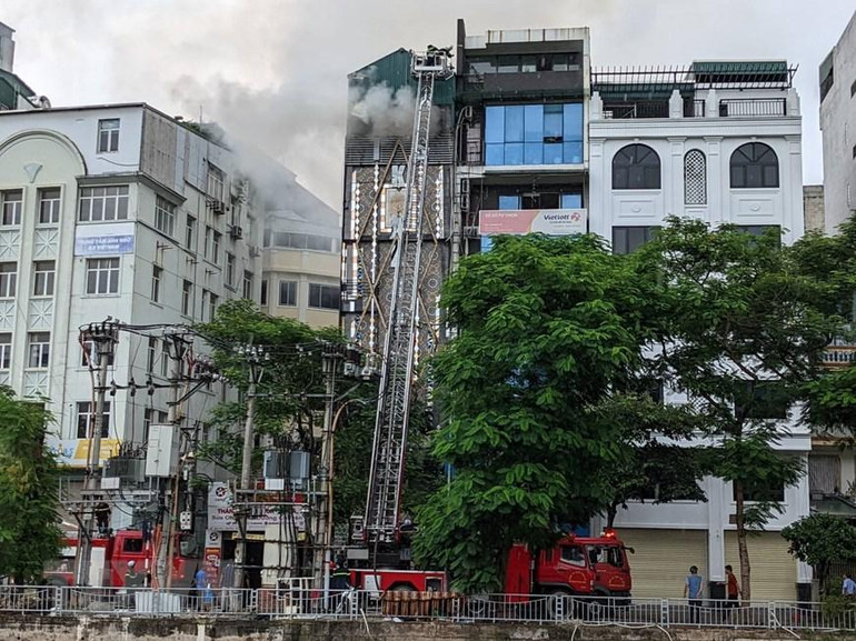 Lực lượng chức năng tìm cách tháo dỡ các bức tường ngăn để tiếp cận khu vực đám cháy ở bên trong, triển khai các biện pháp nghiệp vụ chữa cháy. (Ảnh: TTXVN)