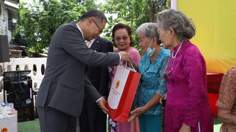 Đại sứ Phan Chí Thành tặng quà cho các kiều bào lão thành.
