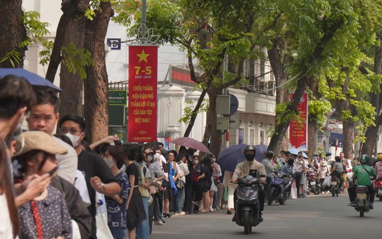 Trời nắng một số bạn chuẩn bị sẵn ô để xếp hàng.