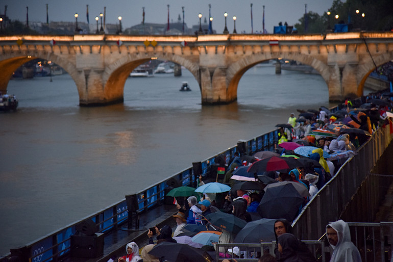 Có rất nhiều thách thức cả về kỹ thuật và an ninh đối với nước chủ nhà khi tổ chức lễ khai mạc ngoài trời và trên sông. Chỉ những phút đầu tiên ngay khi bắt đầu lễ khai mạc, một cơn mưa ngoài ý muốn xuất hiện và có dấu hiệu nặng hạt dần, nhưng vẫn không xua tan đi được không khí náo nhiệt trên hàng ghế khán giả. (Ảnh: KHẢI HOÀN)