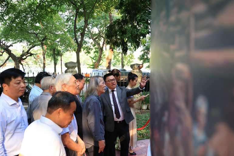 Đồng chí Lê Quốc Minh, Ủy viên Trung ương Đảng, Phó Trưởng Ban Tuyên giáo Trung ương, Tổng Biên tập Báo Nhân Dân, Chủ tịch Hội Nhà báo Việt Nam giới thiệu với họa sĩ Lương Xuân Đoàn và các quan khách, nghệ sĩ về triển lãm tương tác tranh panorama.