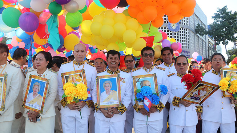 Người tham dự lễ kỷ niệm mang ảnh chân dung cố Quốc vương Norodom Sihanouk, Hoàng Thái hậu Norodom Monineath và Quốc vương Norodom Sihamoni (Ảnh: HUY VŨ)