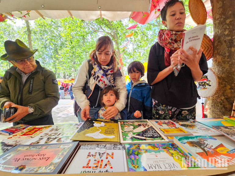 Chị Ariane Louvet cùng các con ghé qua một gian hàng để tìm mua sách truyện tiếng Việt. (Ảnh: KHẢI HOÀN)