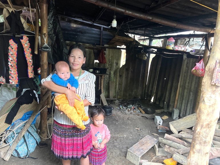 Chị Giàng Thị Lề đang bế đưa con thứ 12 mới được 4 tháng tuổi bên trong căn nhà cũ. (Ảnh: MINH PHƯƠNG)