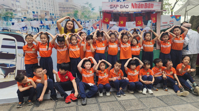 Các em học sinh Trường tiểu học Tràng An thích thú cùng cô giáo chụp ảnh tại Triển lãm. (Ảnh: SƠN BÁCH)