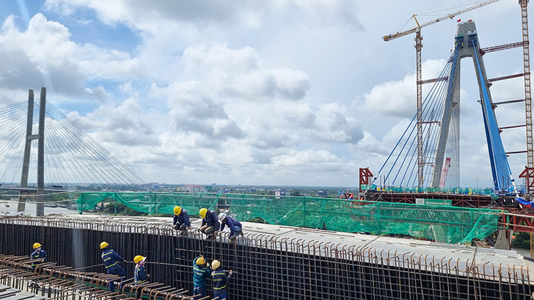 Công nhân lao động đang làm việc trên công trường, đoạn chuẩn bị nối nhịp chính của cây cầu.