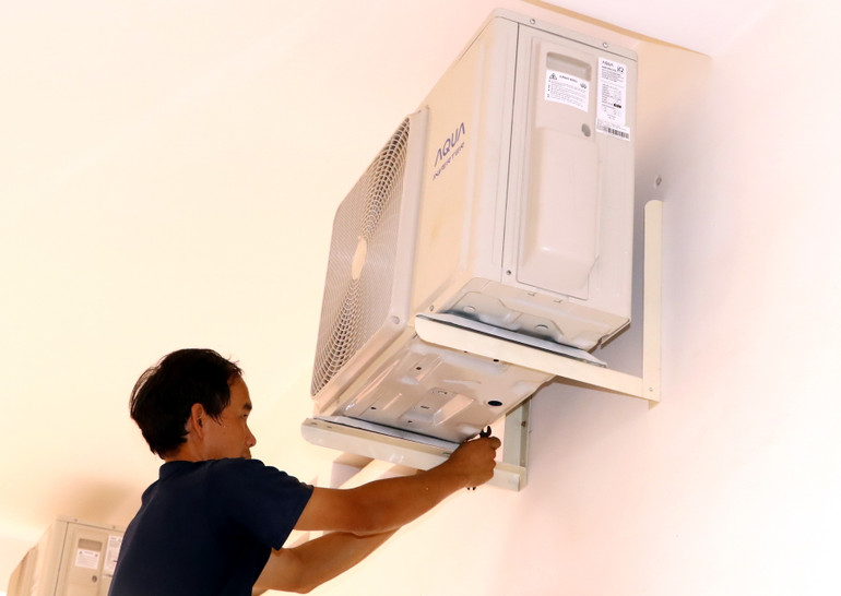 Đơn vị thi công tiến hành lắp đặt cục nóng của máy lạnh ở bên ngoài phòng học.