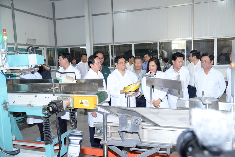 Thủ tướng Phạm Minh Chính nghe giới thiệu về sản phẩm gạo tại dây chuyền đóng gói gạo của VINARICE.