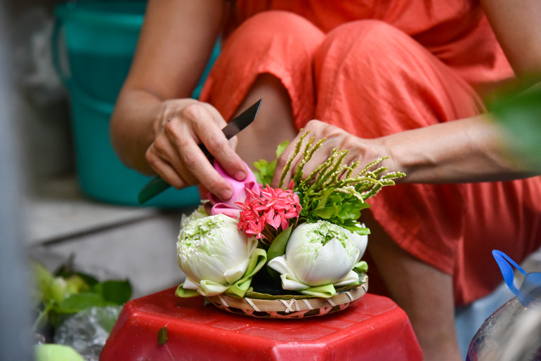 Một người bán đang cẩn thận, tỉ mẩn làm đồ trang trí mâm cho khách.