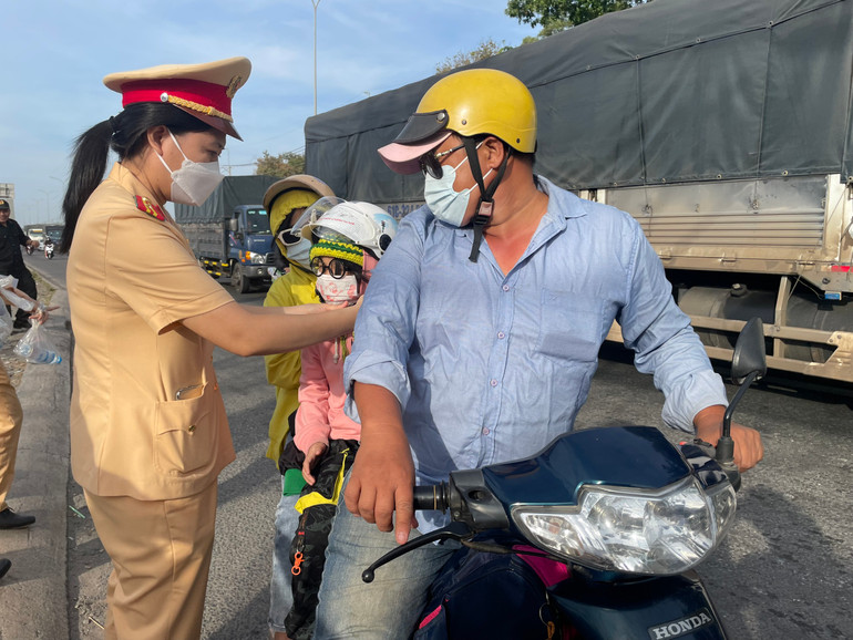 Nữ Cảnh sát giao thông Công an tỉnh Đồng Nai thay mũ bảo hiểm cho một em bé.