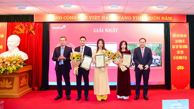 Đồng chí Hồ Xuân Trường - Phó Bí thư Đảng ủy Khối Doanh nghiệp Trung Ương (bên phải) và đồng chí Trần Minh Bình - Ủy viên Ban Chấp hành Đảng bộ Khối Doanh nghiệp Trung Ương, Bí thư Đảng ủy, Chủ tịch Hội đồng quản trị Ngân hàng Công thương Việt Nam (bên trái) trao Giấy chứng nhận và hoa cho các tác giả/nhóm tác giả đạt giải Nhất.