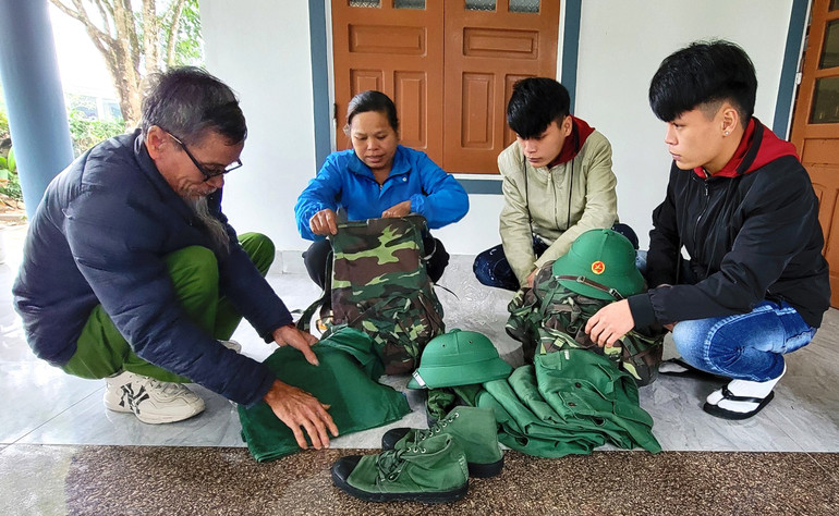 Ông Phạm Công Tiến giúp đỡ, hướng dẫn hai con trai sắp đặt ba lô, quân tư trang cá nhân trước ngày lên đường nhập ngũ.