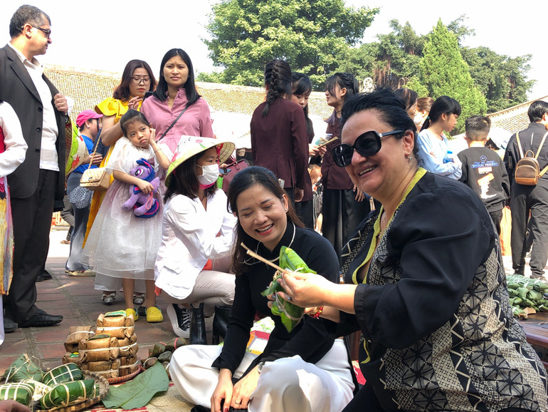 Khách nước ngoài thích thú thử gói bánh chưng.