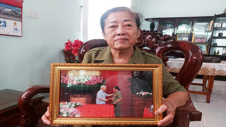 Nữ Anh hùng Lưu Nguyệt Hồng và bức ảnh được Tổng Bí thư Nguyễn Phú Trọng ân cần thăm hỏi, động viên.