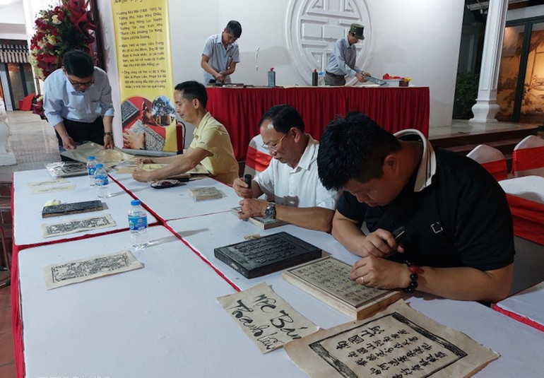 Các nghệ nhân làng nghề khắc mộc bản Thanh Liễu (Hải Dương) trình diễn kỹ thuật khắc tranh, sách để in trên giấy dó.