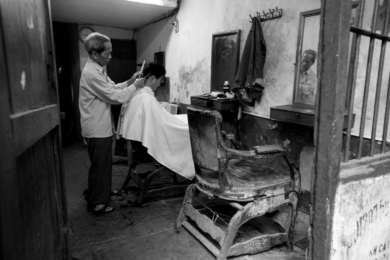 Cắt tóc, một hình ảnh quen thuộc về cuộc sống Hà Nội. (Ảnh: Lê Bích)