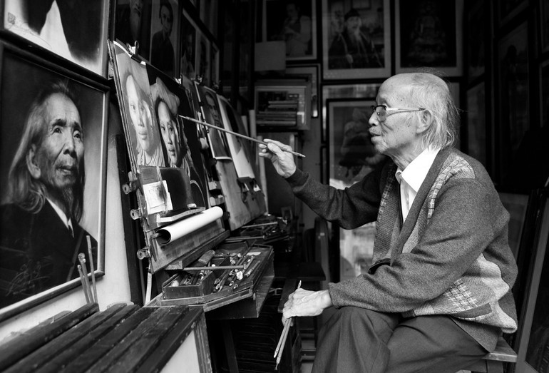 Nghệ nhân vẽ truyền thần Nguyễn Bảo Nguyên trong căn nhà trên phố Hàng Ngang. (Ảnh: Lê Bích)