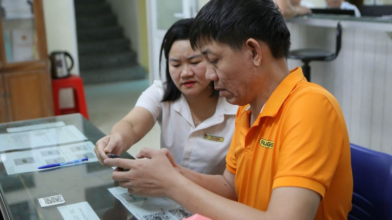 Cán bộ phường hướng dẫn người dân giải quyết thủ tục hành chính thông qua cổng dịch vụ công. (Ảnh minh họa: TTXVN)