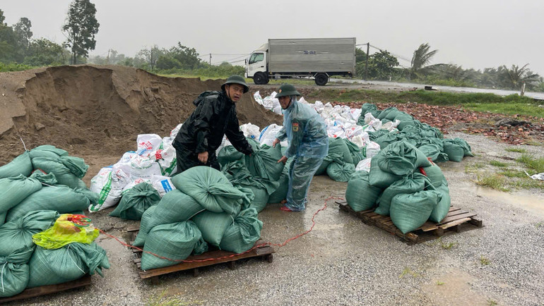 Lực lượng hộ đê đang cho cát vào các bao tải để phòng gia cố đê kè, trong khi mưa bắt đầu to hơn. (Ảnh: MAI TÚ) Lực lượng hộ đê đang cho cát vào các bao tải để phòng gia cố đê kè, trong khi mưa bắt đầu to hơn. (Ảnh: MAI TÚ)