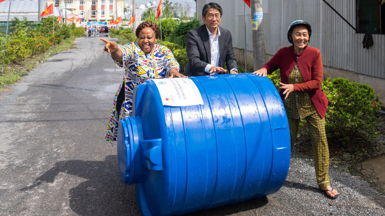 Trưởng Đại diện UN Women tại Việt Nam, bà Caroline Nyamayemombe và Đại sứ Nhật Bản tại Việt Nam, ông Ito Naoki cùng người dân Cà Mau chuyển bồn nước về nhà.