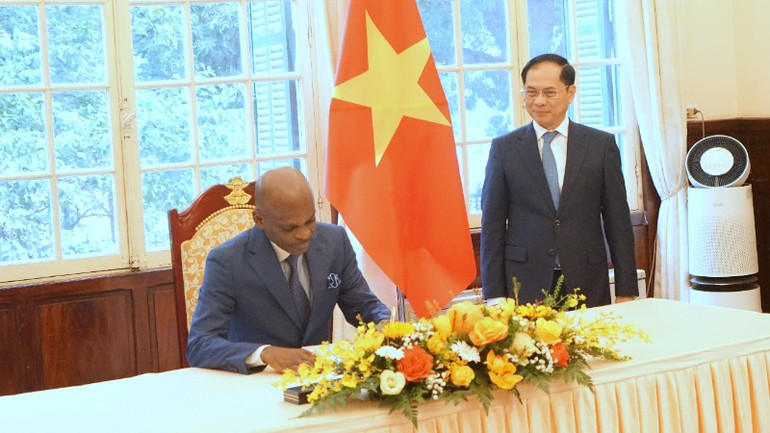 Bộ trưởng Ngoại giao, Hội nhập khu vực và Kiều dân Cộng hòa Togo Robert Dussey viết sổ lưu bút. (Ảnh: TRUNG HƯNG)