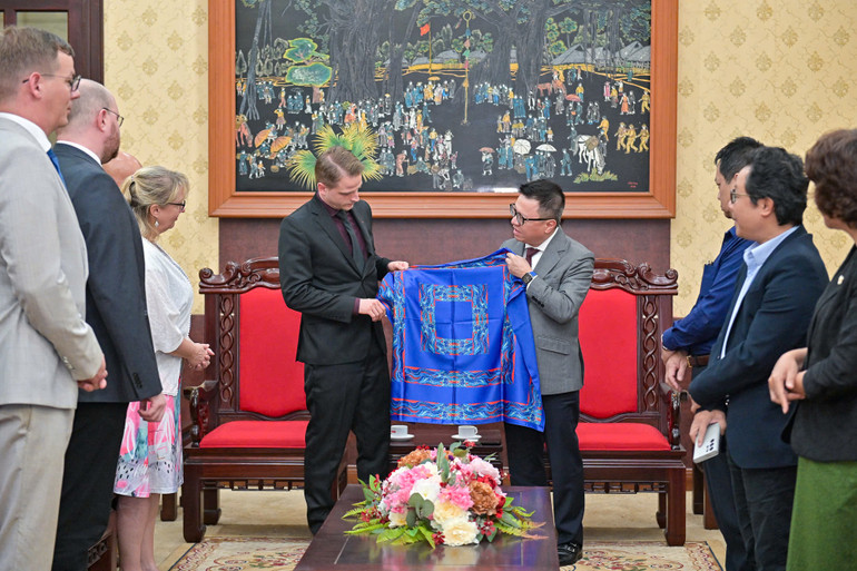 Tổng Biên tập Lê Quốc Minh tặng quà lưu niệm chiếc khăn lụa Bảo Lộc có in logo Báo Nhân Dân cho Phó Chủ tịch Đảng Cánh tả Đức Maximilian Schirmer. (Ảnh: THẾ ĐẠI)