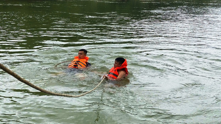 Lực lượng cứu nạn, cứu hộ móc dây vào xe bị nạn để kéo lên bờ.