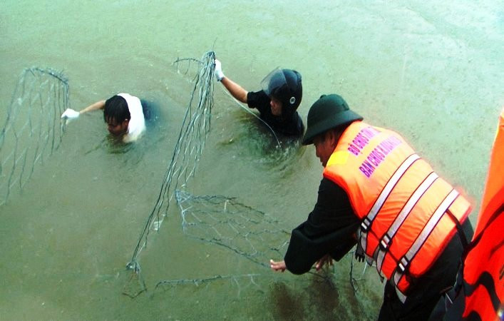 Việc xếp kè rọ đá vào vị trí bị sạt lở rất khó khăn, cán bộ, chiến sĩ và các lực lượng phải ngâm mình dưới nước để thực hiện.