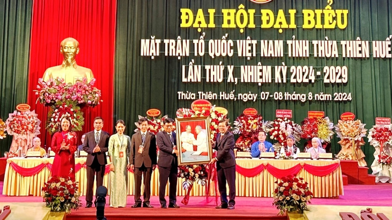 Phó Chủ tịch Ủy ban Trung ương Mặt trận Tổ quốc Việt Nam Nguyễn Hữu Dũng trao bức tranh Bác Hồ, Bác Tôn của Ủy ban Trung ương Mặt trận Tổ quốc Việt Nam tặng Đại hội.