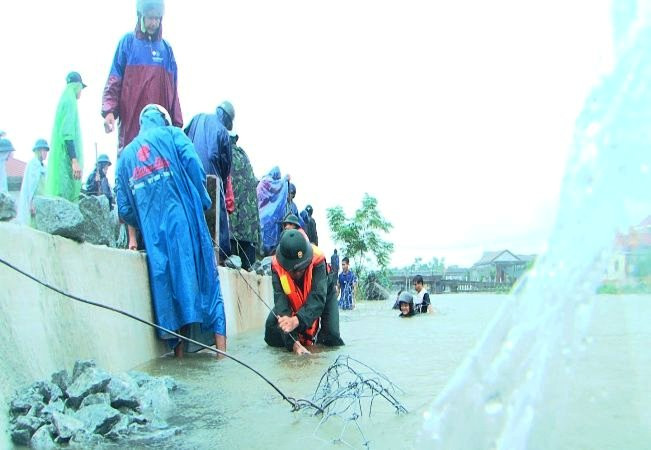 Cán bộ, nhân viên Ban Chỉ huy Quân sự huyện Quảng Điền tham gia giúp dân chống sạt lở đê.