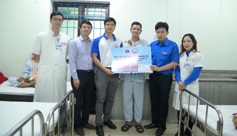 Trao quà cho gia đình ông Trần Đình Minh bị sạt lở hoàn toàn căn nhà tại xã Bình Tiến, hiện đang cấp cứu tại Bệnh viện Trung ương Huế. (Ảnh: BVH)