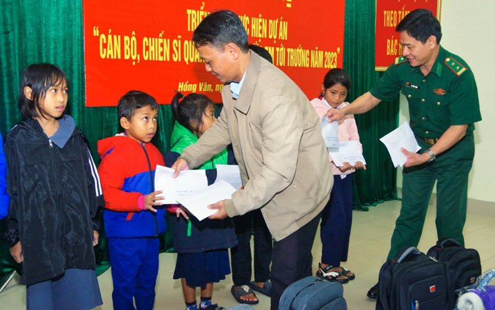 Đại diện Đồn biên phòng cửa khẩu Hồng Vân và chính quyền địa phương trao kinh phí hỗ trợ cho các em học sinh. (Ảnh: Hồng Minh).