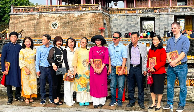 Du khách thích thú chụp hình cùng những cuốn lịch được tặng tại Lễ Ban Sóc.