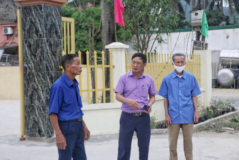 Ông Hoàng Đức Ân (ở giữa) trao đổi với cán bộ thôn, xóm về tình hình xây dựng nông thôn mới.