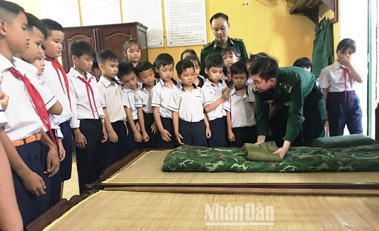 Các em học sinh được cán bộ Bộ đội Biên phòng giới thiệu cách xếp đặt nội vụ.